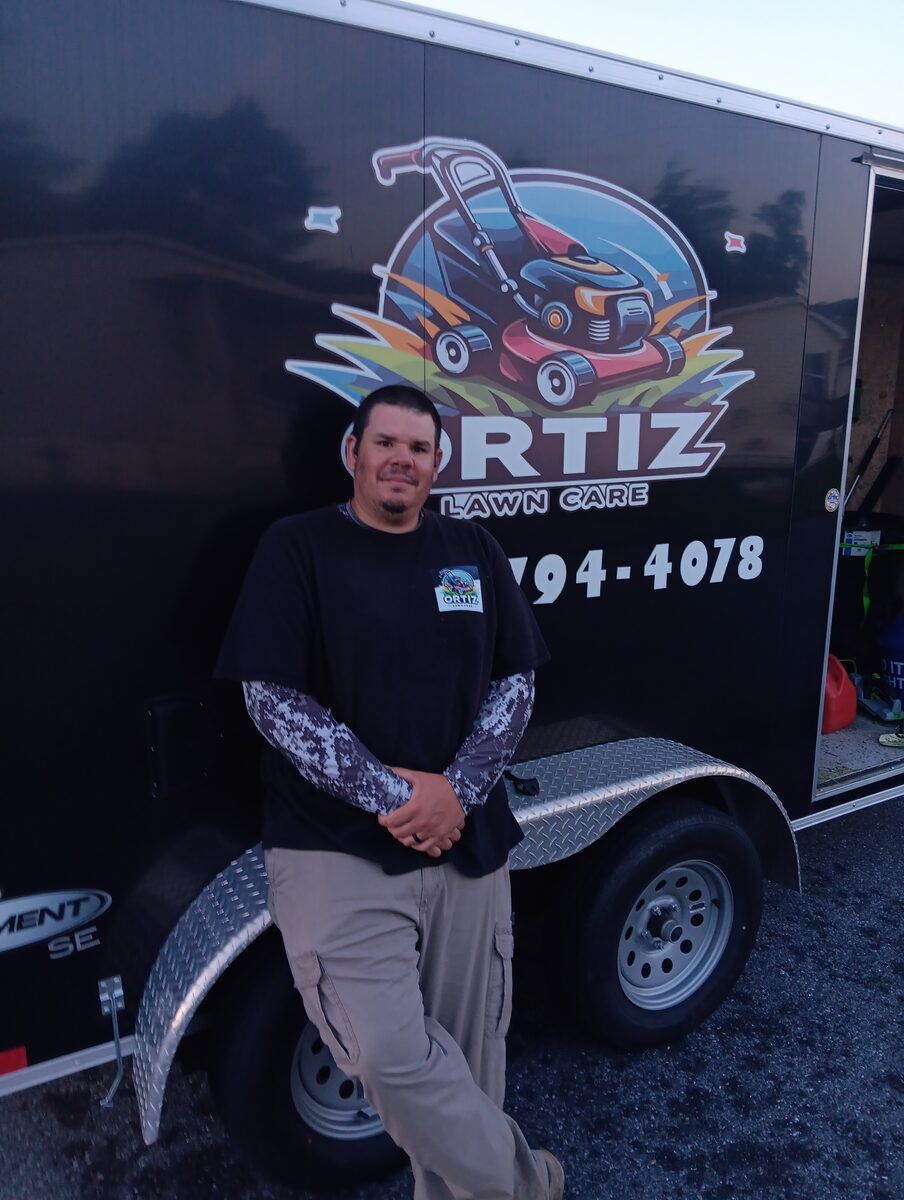 Pedro, owner of Ortiz Lawn Care, in front of the company trailer